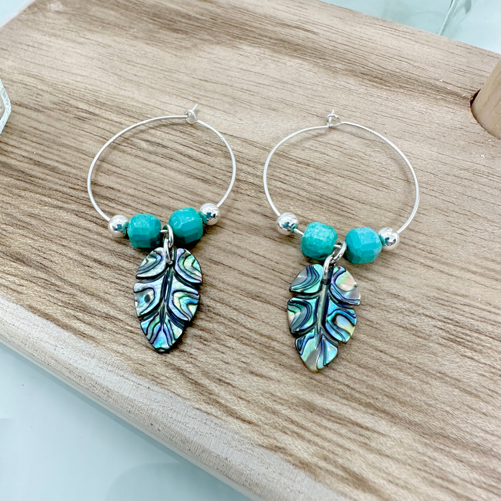 Sterling silver hoop earrings with carved abalone shell leaf charms and turquoise gemstone beads, handmade UK jewellery